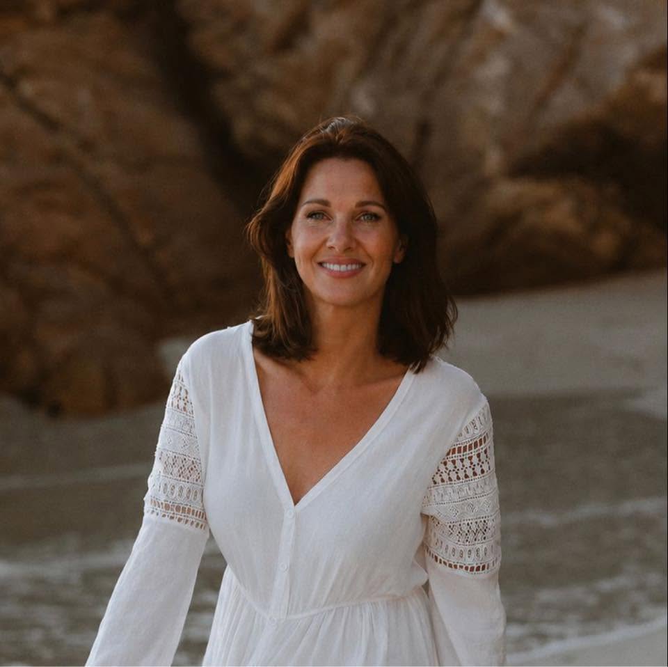 Janine, IEMT-practitioner, wandelt ontspannen langs de zee in warm avondlicht.